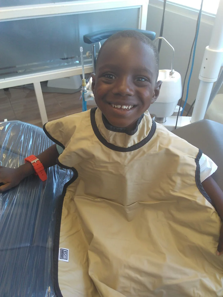 A young patient smiling with a dental bib during a visit