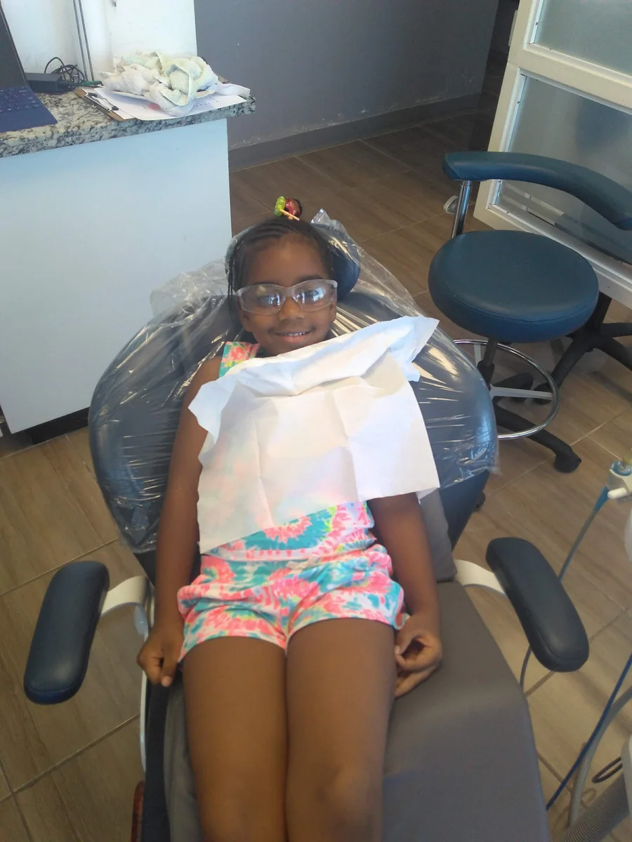 A young patient relaxing in the dental chair with protective glasses and a bib