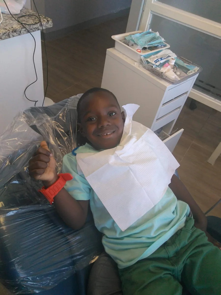 A smiling young patient giving a thumbs up in the dental chair
