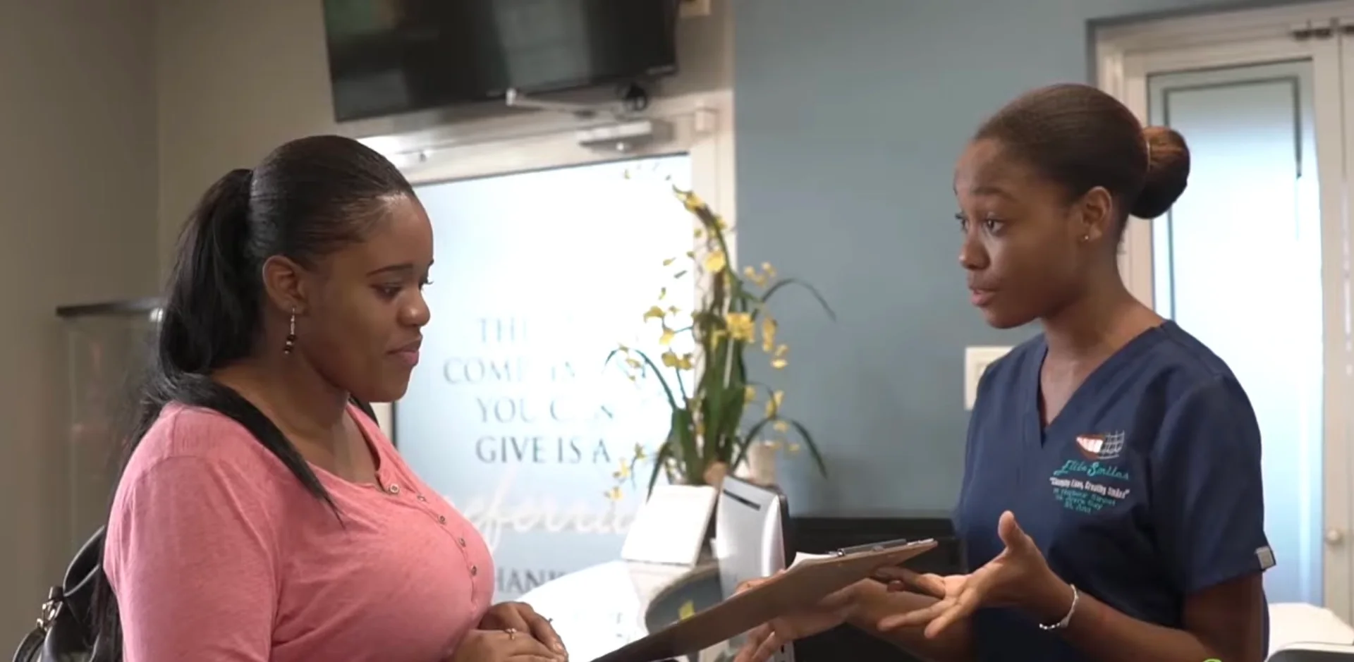 An Elite Smiles team member speaking with a visitor at reception